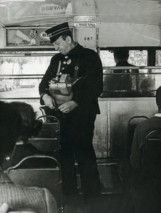 1967. Con rgida uniformidad, gorra incluida, un cobrador desempea su trabajo a bordo de un autobs (con el volante a la derecha)